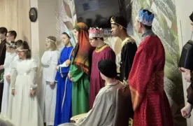 Fragment występu uczniów w zakładzie opiekuńczym. Uczniowie przebrani są za postacie  związane z narodzeniem  Jezusa.  Z prawej strony zdjęcia siedzi pani katechetka z gitarą oraz stoi  jedna z pan wychowawczyń szkoły.