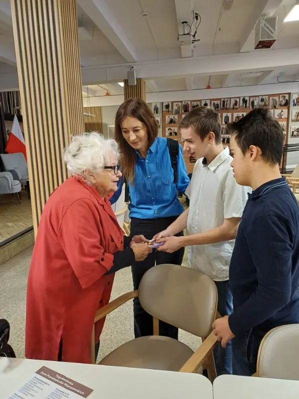 Dwoje uczniów naszej szkoły wraz z nauczycielką rozmawiają z  uczestniczką Powstania Warszawskiego w Domu Powstańców Warszawskich                           jedną z  weteranek Powstania Warszawskiego w Domu Powstańców Warszawskich