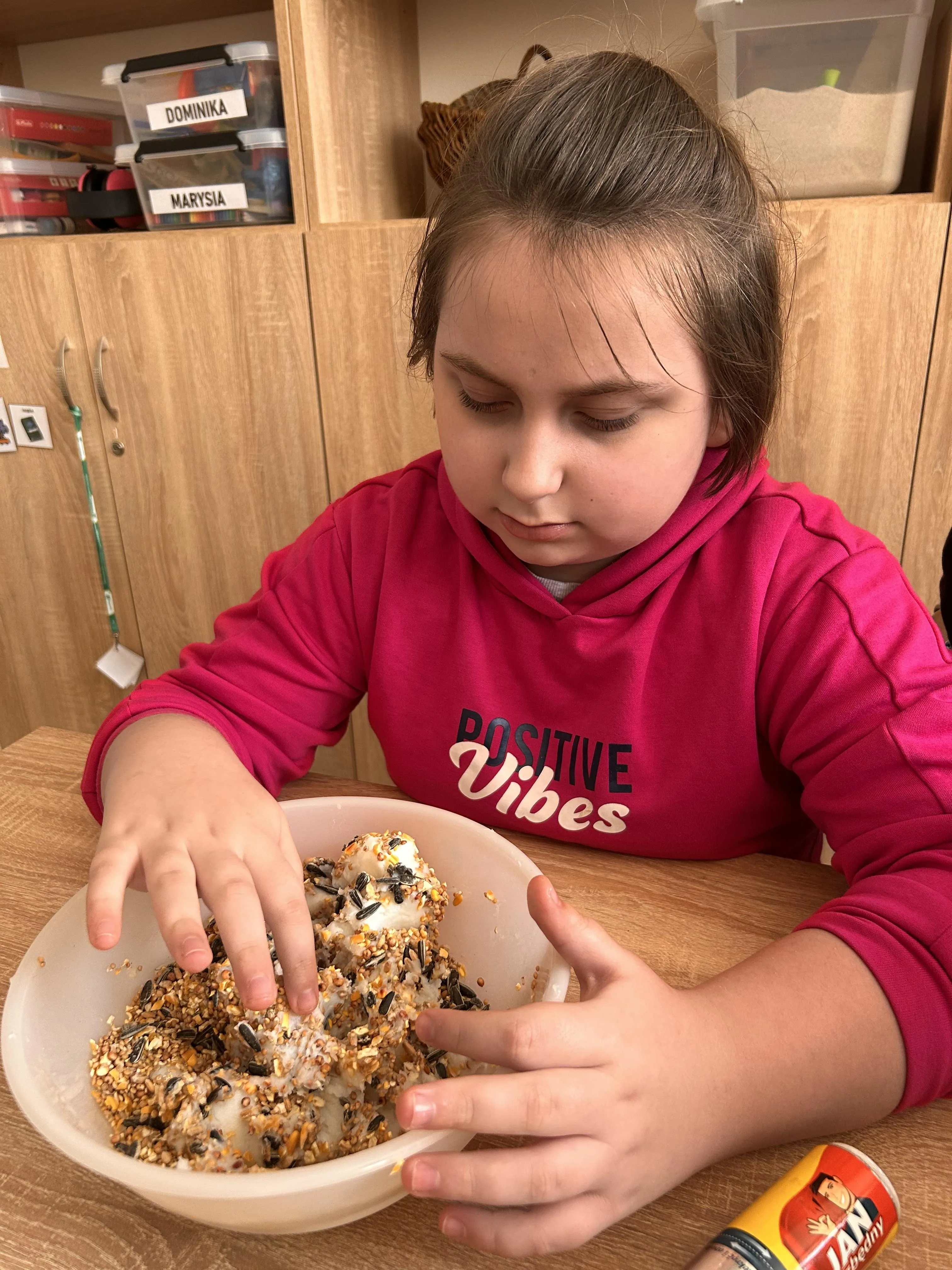 Uczennica przygotowuje kulę pokarmową dla ptaków 