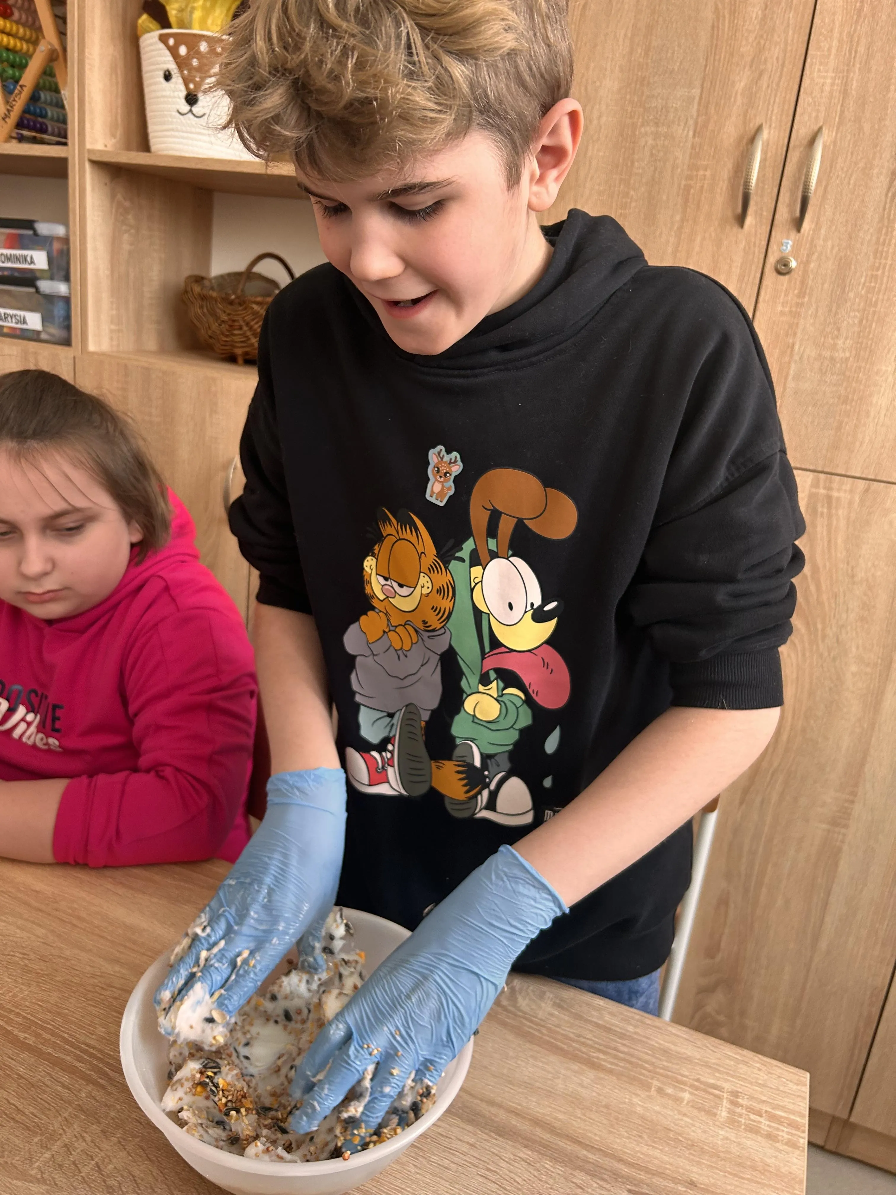 Uczeń przygotowuje kulę pokarmową dla ptaków 