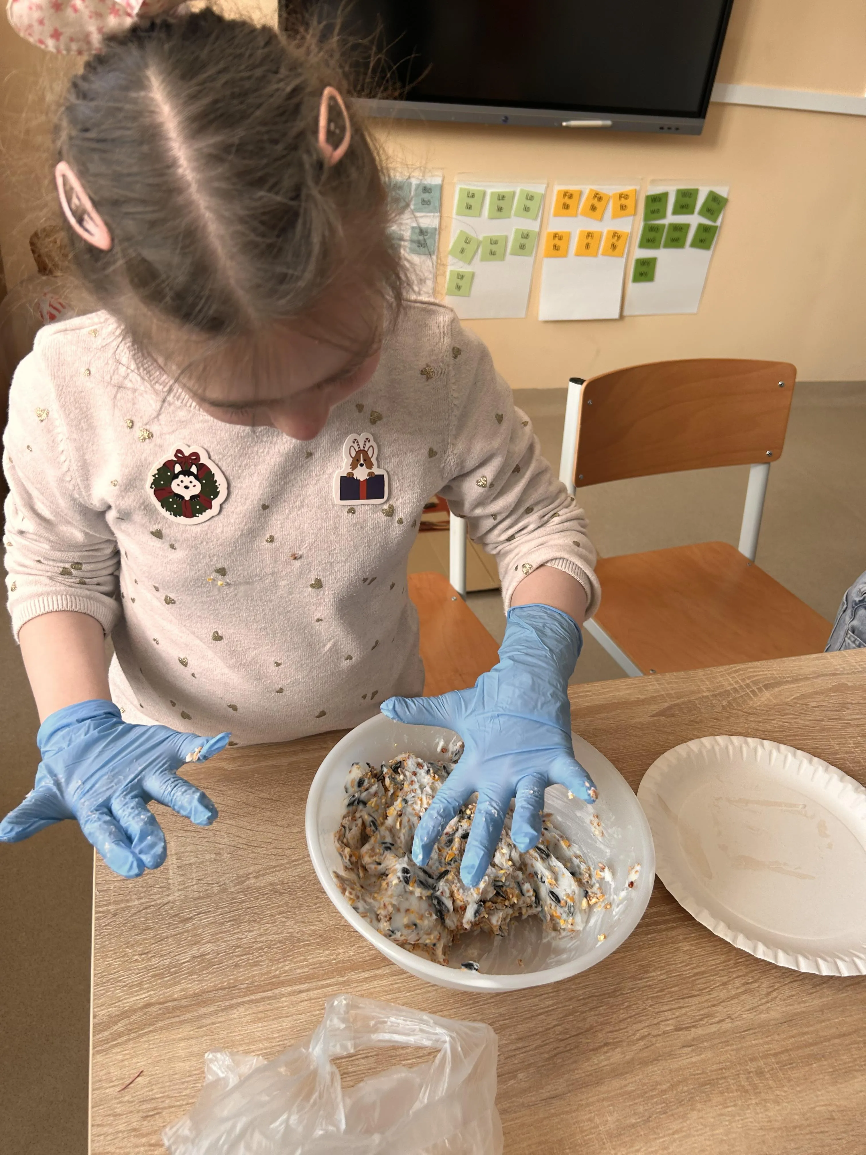 Uczennica miesza w misce składniki na kule pokarmowe dla ptaków