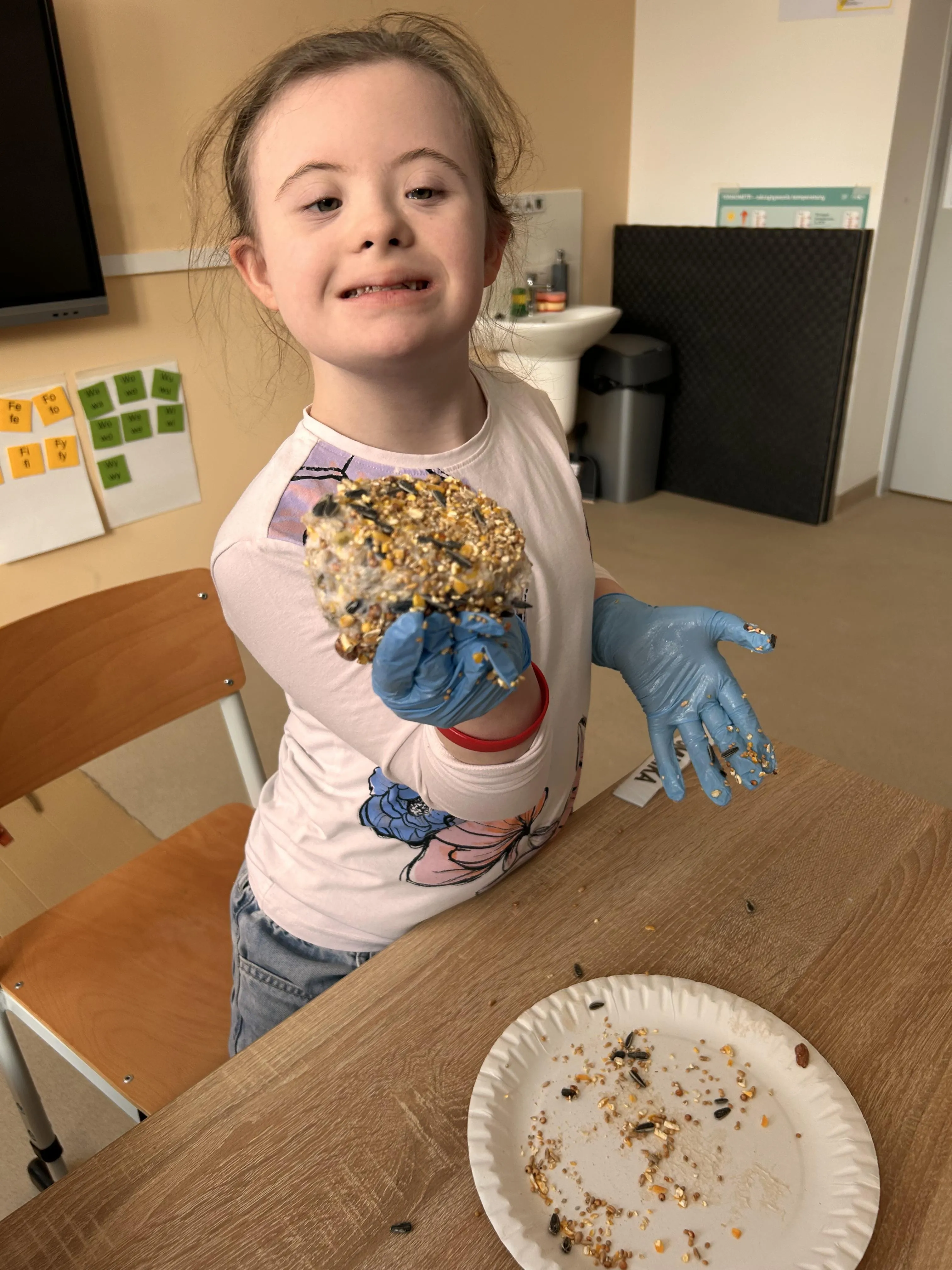 Uczennica prezentuje przygotowaną kulę pokarmową dla ptaków