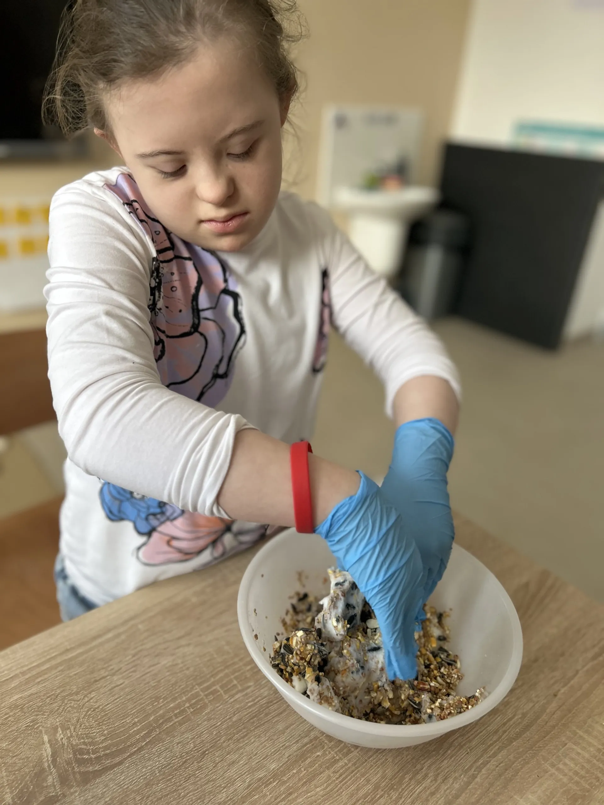 Uczennica miesza  w misce składniki na  pokarm dla ptaków