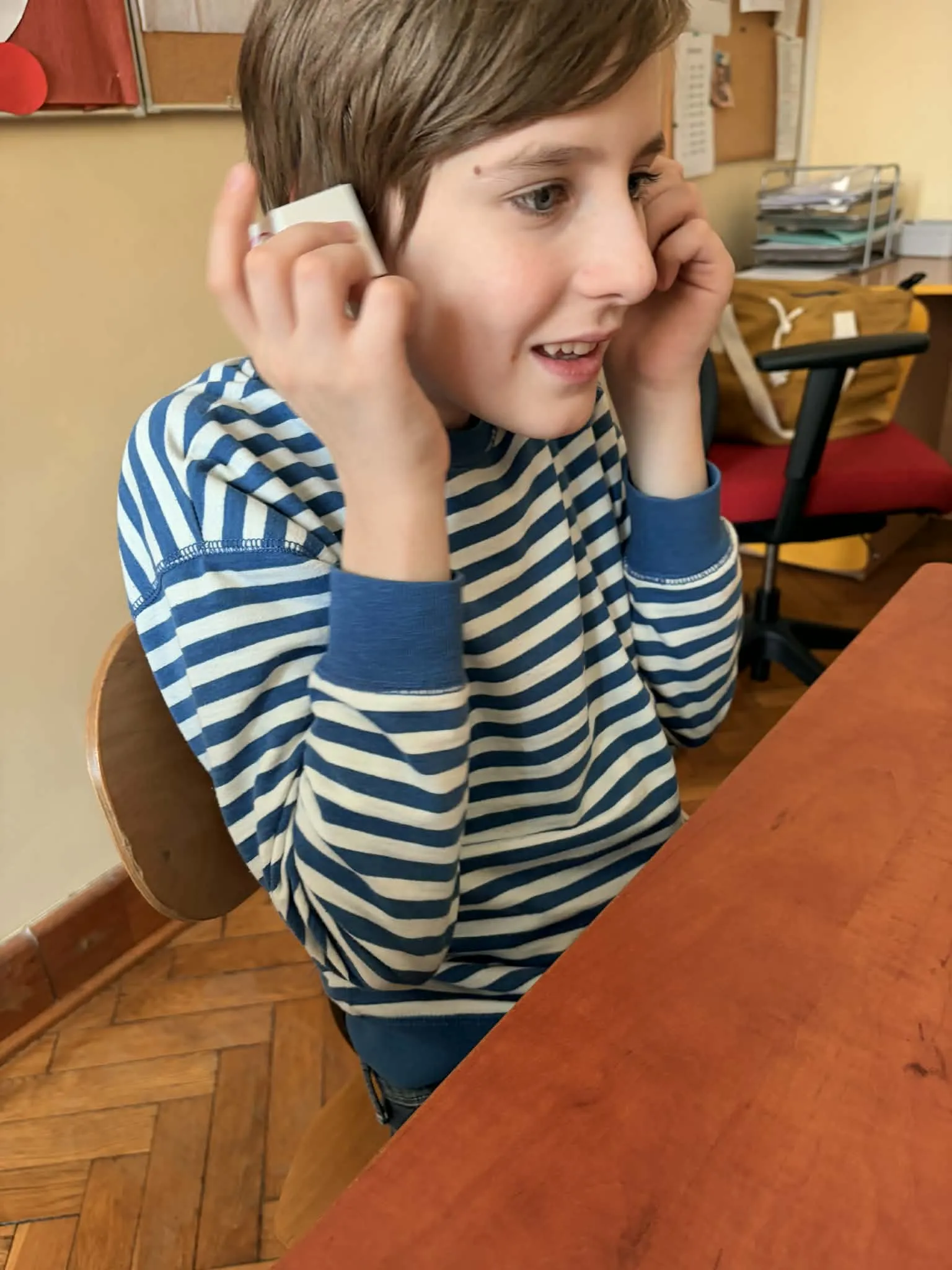 Uczeń siedzi przy stoliku ze słuchawkami w uszach i odsłuchuje dźwięki 