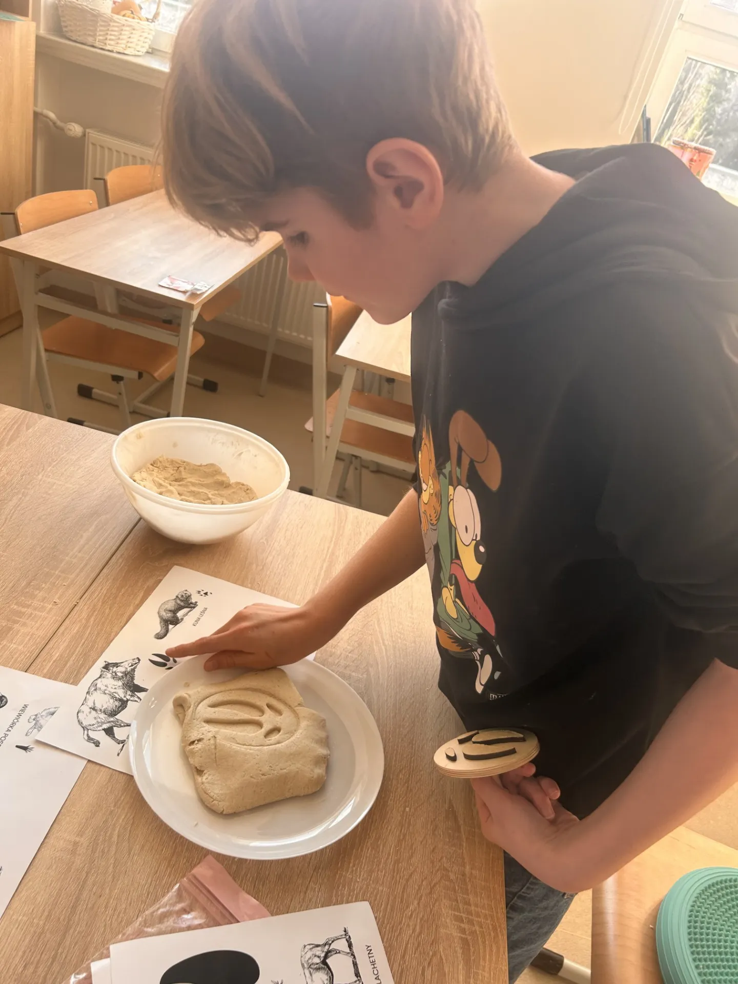 Uczeń  odbija w masie solnej przy pomocy drewnianego klocka ślady zwierząt