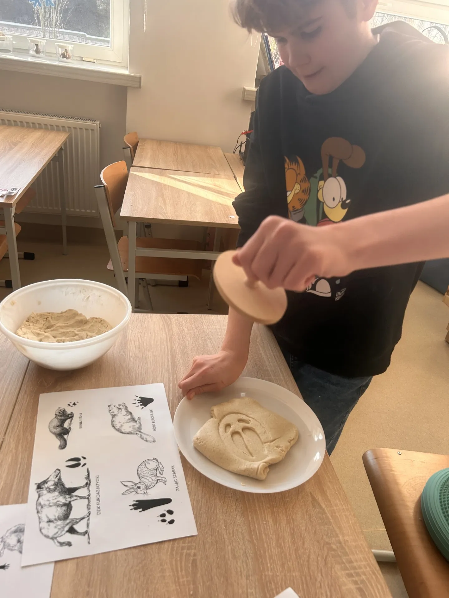 Uczeń  wyciska w masie solnej przy pomocy drewnianego klocka ślady zwierząt