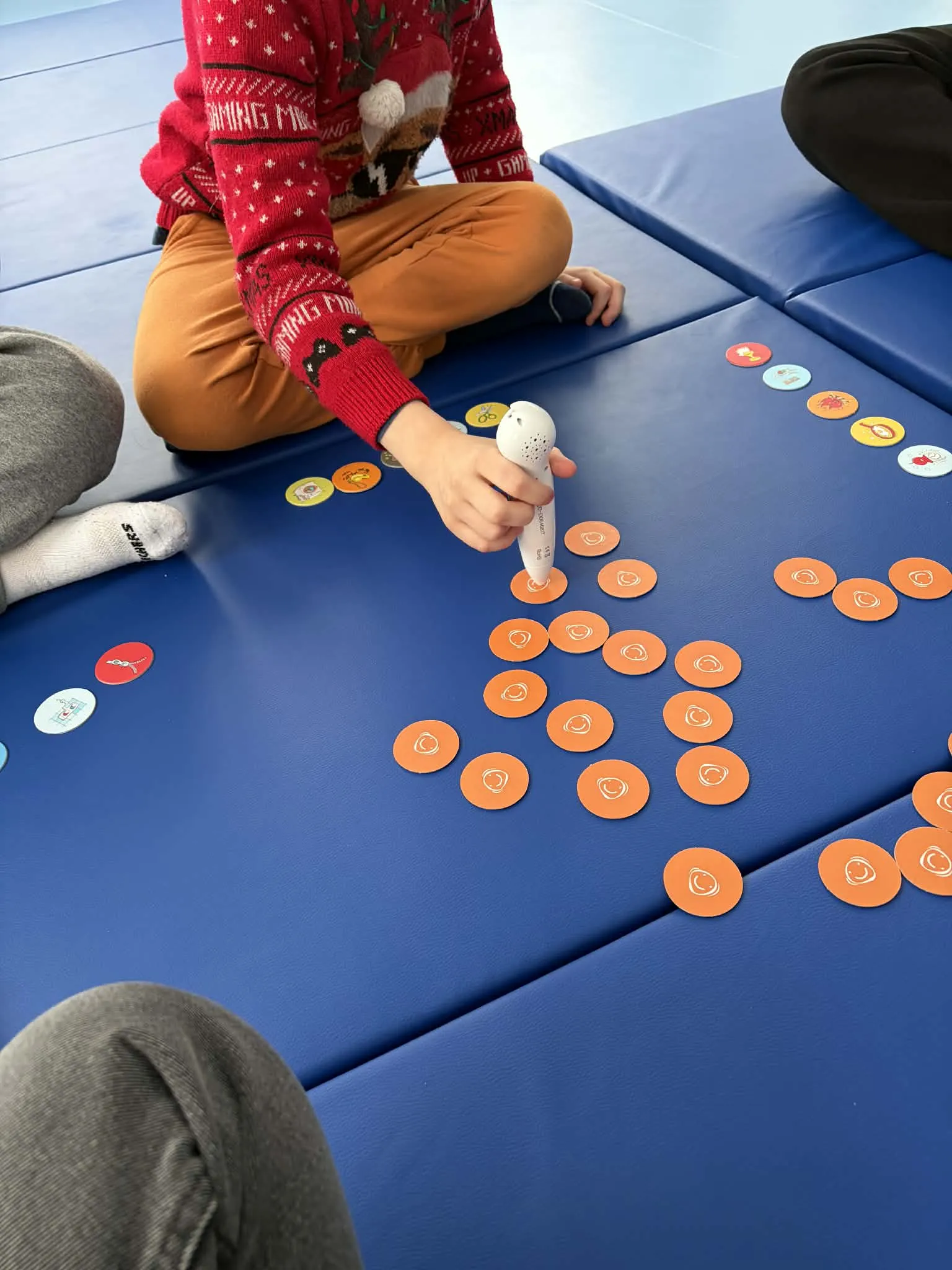 uczennica przy ćwiczeniu wykorzystującym pióro elektroniczne do odtwarzania dźwięków podczas dotykania leżących na kartonie krążków 