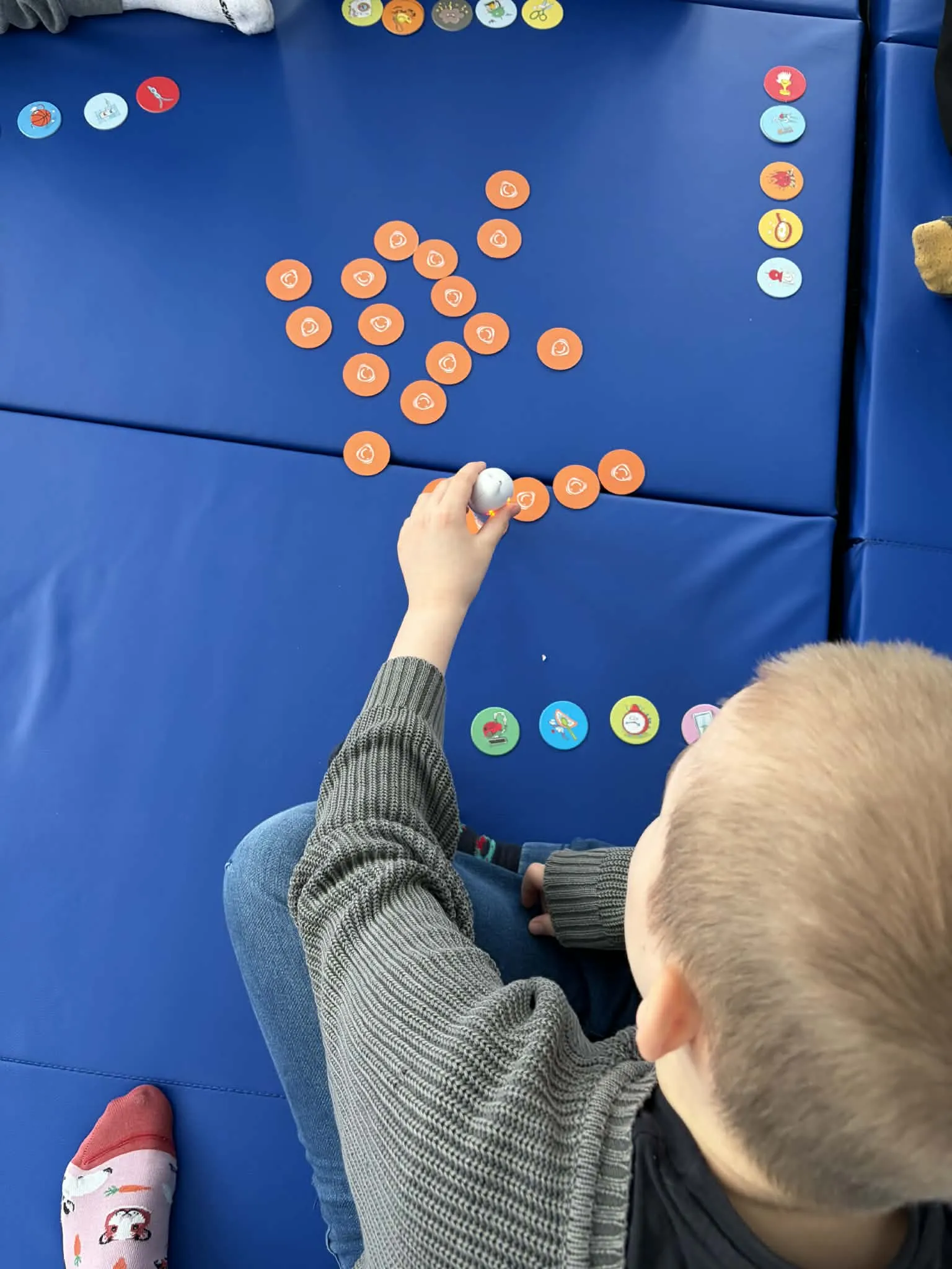 Uczeń przy pomocy pióra elektronicznego odsłuchuje dźwięki dotykając rozłożonych na kartonie krążków