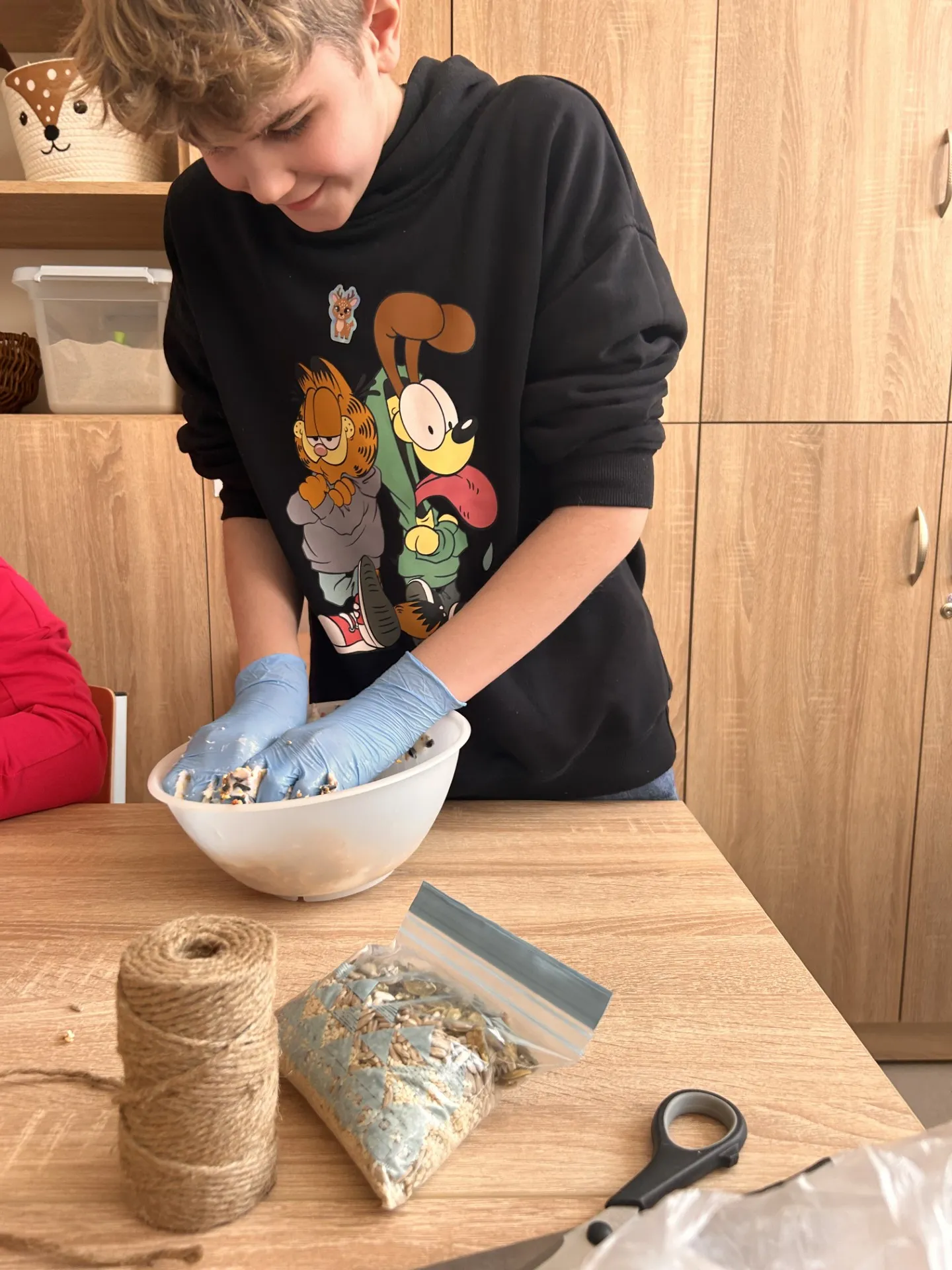 Uczeń przygotowuje pokarm dla zwierząt, mieszając składniki w misce