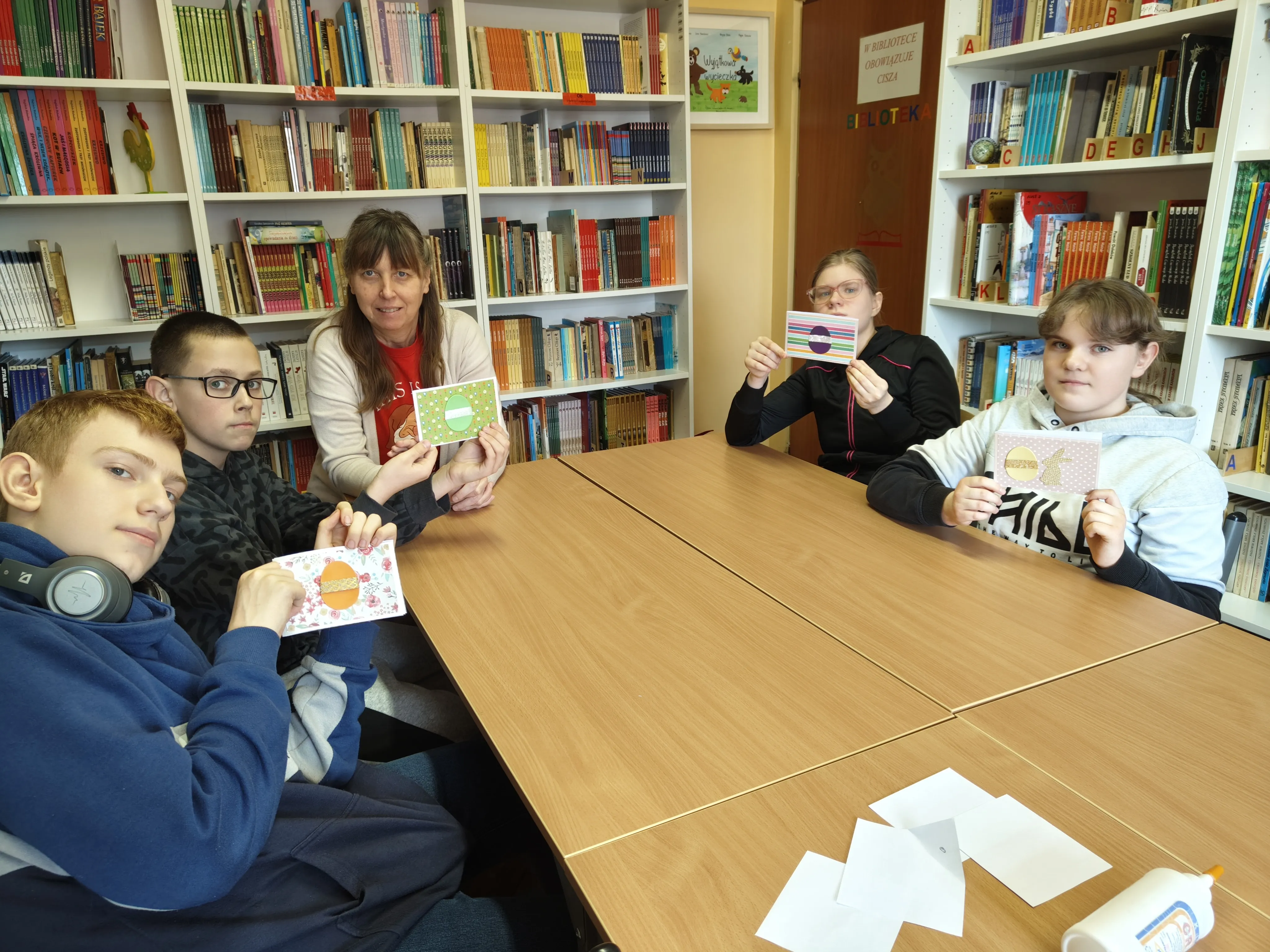 Uczniowie klasy 7a wraz z wychowawczynią w bibliotece szkolnej - prezentują wykonane kartki świąteczne