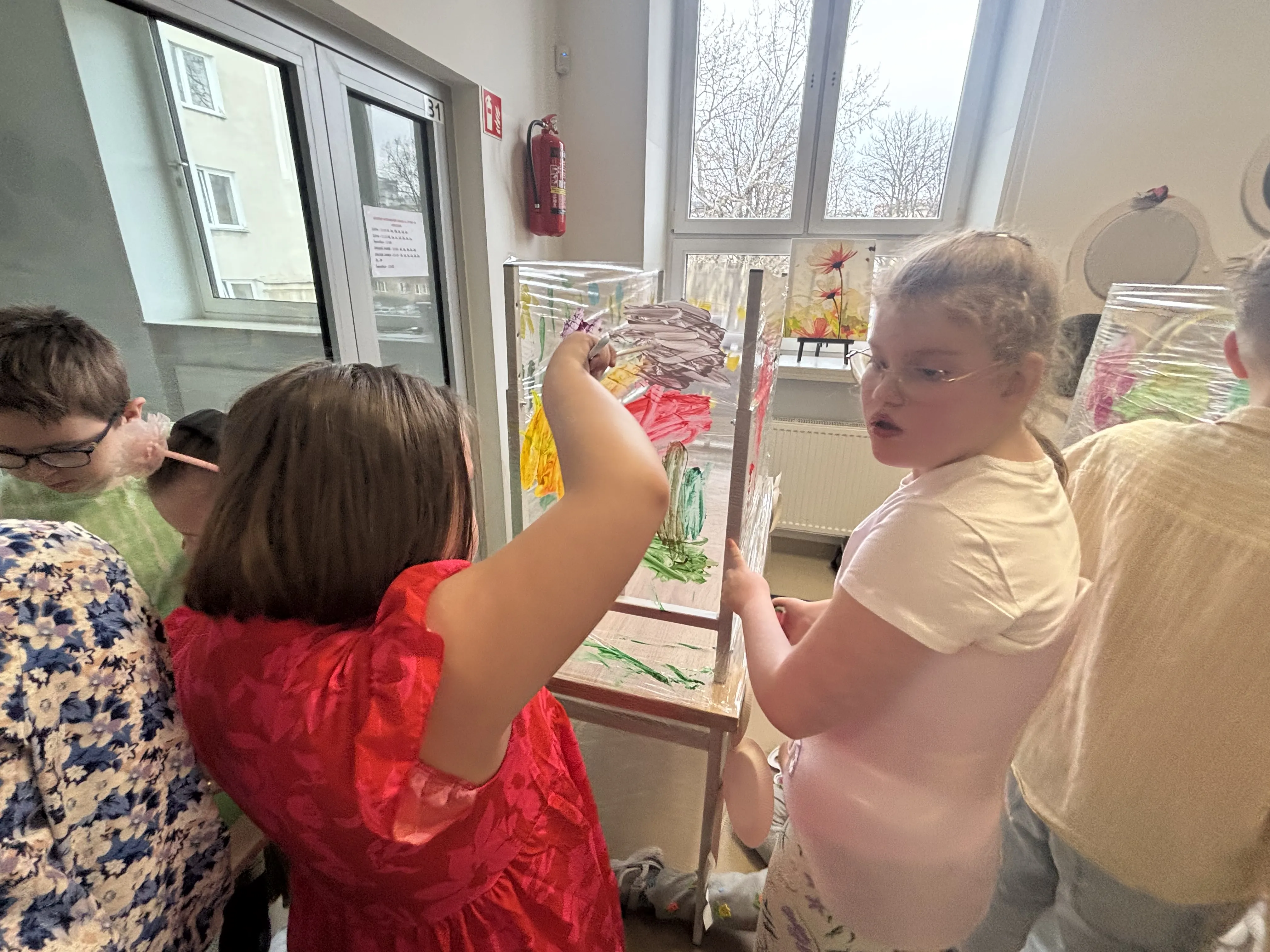 Na zdjeciu znajduje się paru uczniów, którzy wykonują "malowanki" na  szklanych taflach