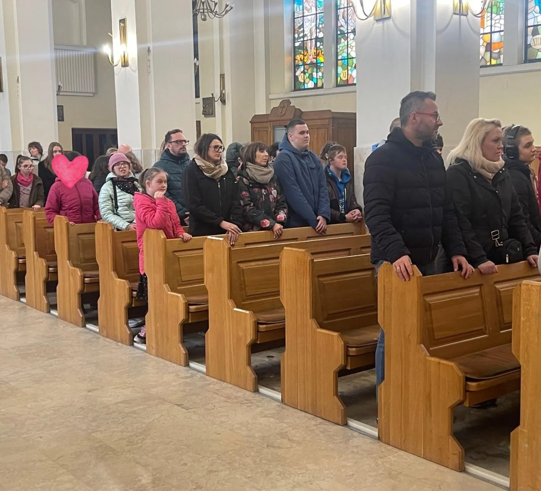 uczniowie i nauczyciele stojący w ławkach w kościele