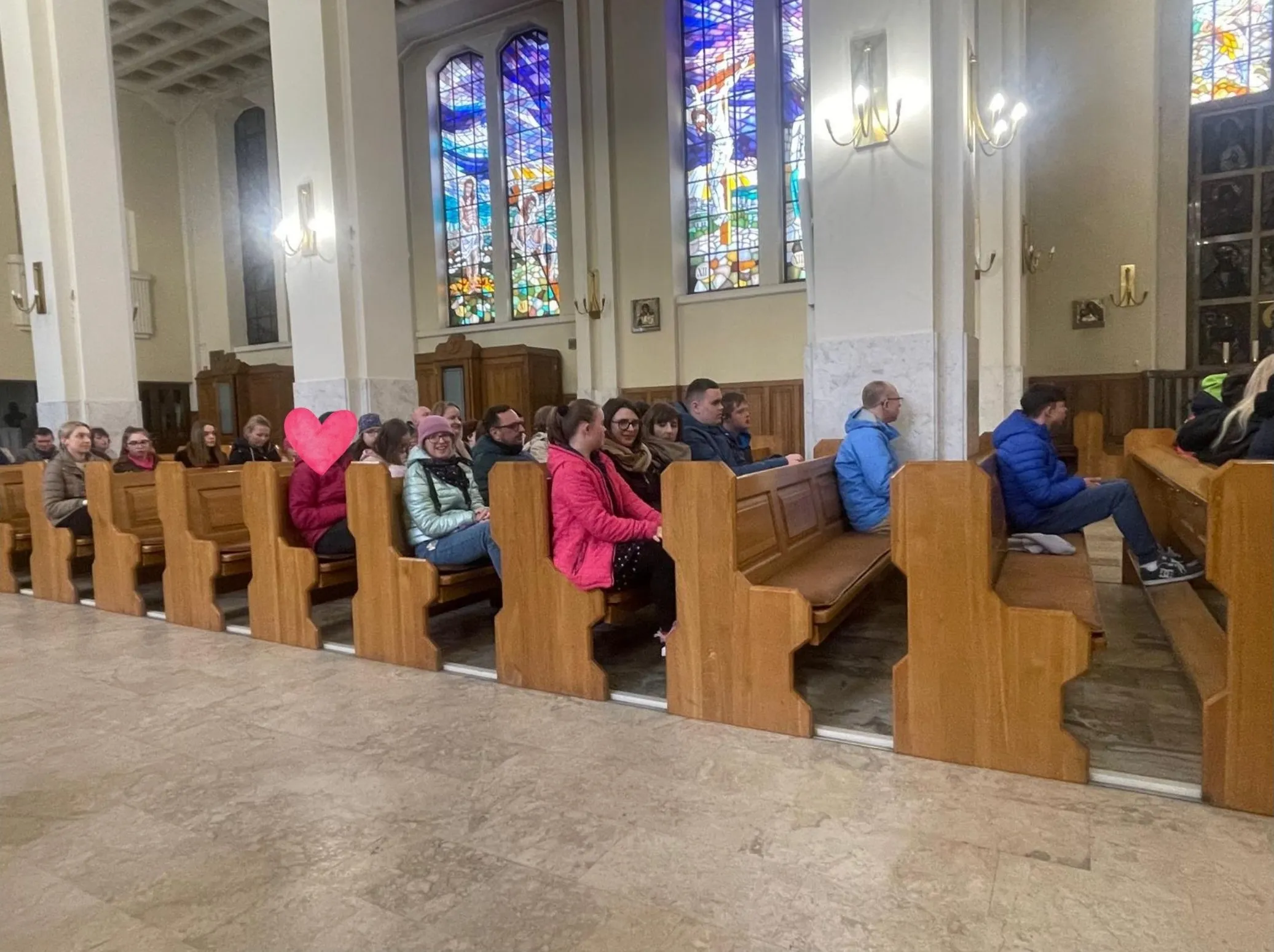 uczniowie i nauczyciele siedzacy w ławkach w kościele