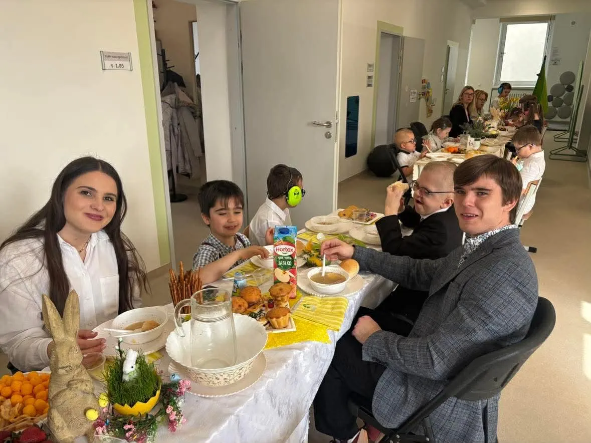 uczniowie i nauczyciele siedzacy przy stołach w przy śniadaniu wielkancnym