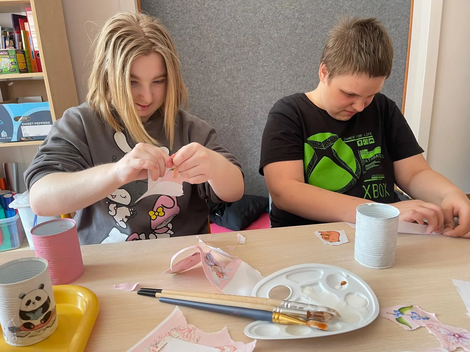 dziewczynka i chłopiec wyklajają puszki