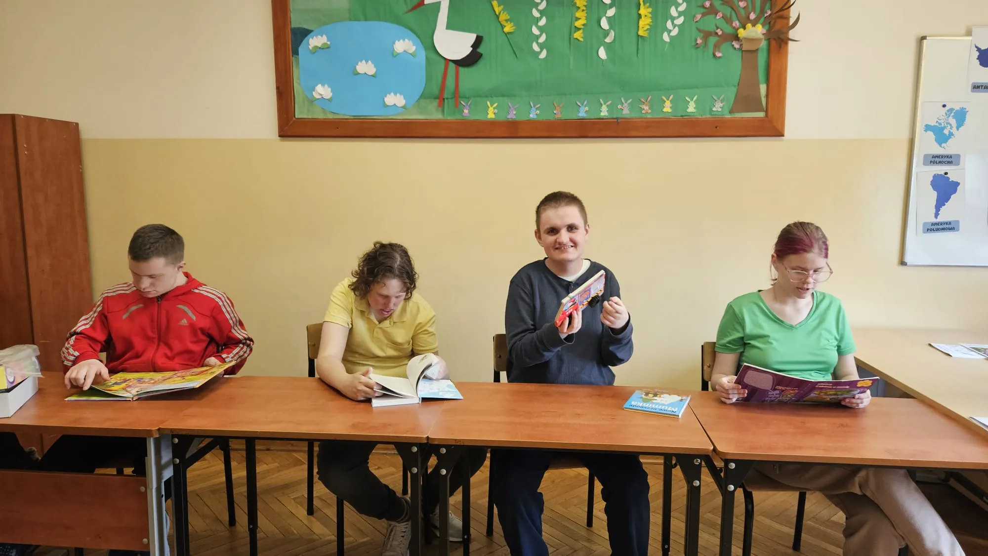 uczniowie siedza szkolnym z ksiazkami