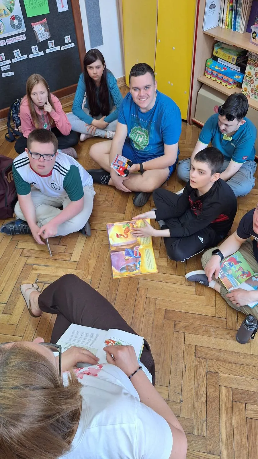 uczniowie siedza na podłodze z ksiazkami