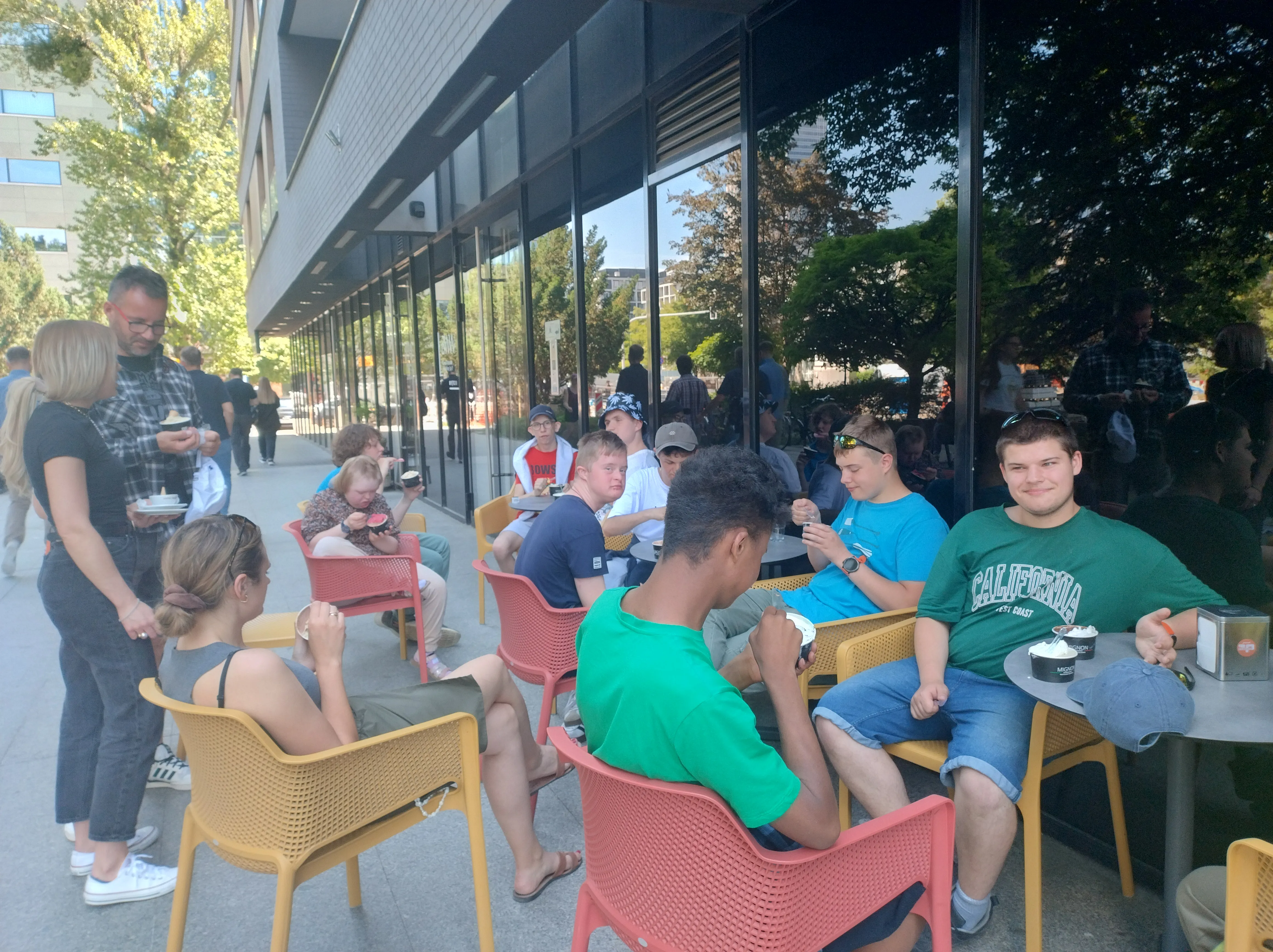 Na zdjęciu uczniowie, siedzący przy stolikach  przy barze restauracyjnym, obok stoi nauczyciel WF  i  pani Agnieszka - pomoc nauczyciela nauczyciela.