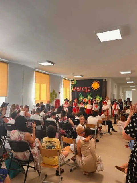 Występ  dzieci z klas 1-3, w meksykańskich  strojach,  którzy stoją przed widownią na korytarzu szkolnym na tle wakacyjnej dekoracji.